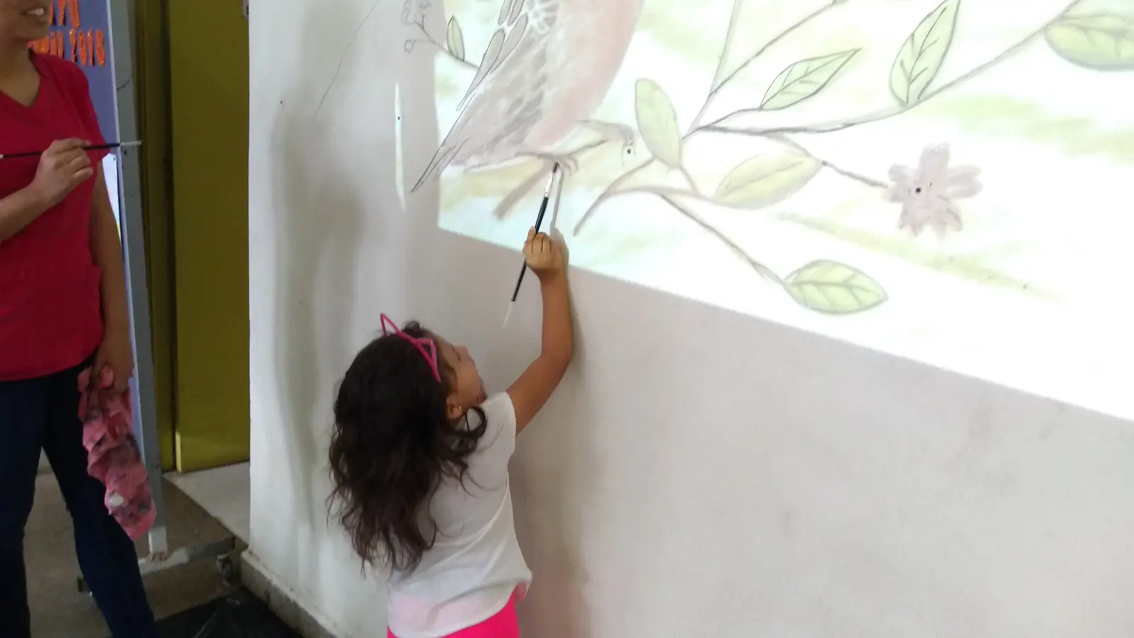 Proceso de facilitacion mural con participantes pintando en un muro del CESFAM Villa Los Quillayes